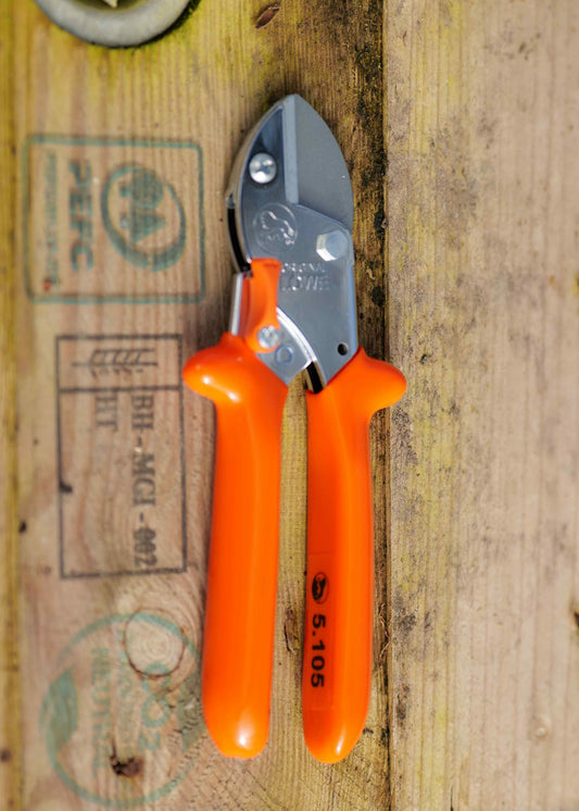 Orange-handled Lowe Small Anvil Cutters with a silver metal blade, resting on a rustic wooden surface with stamp markings.