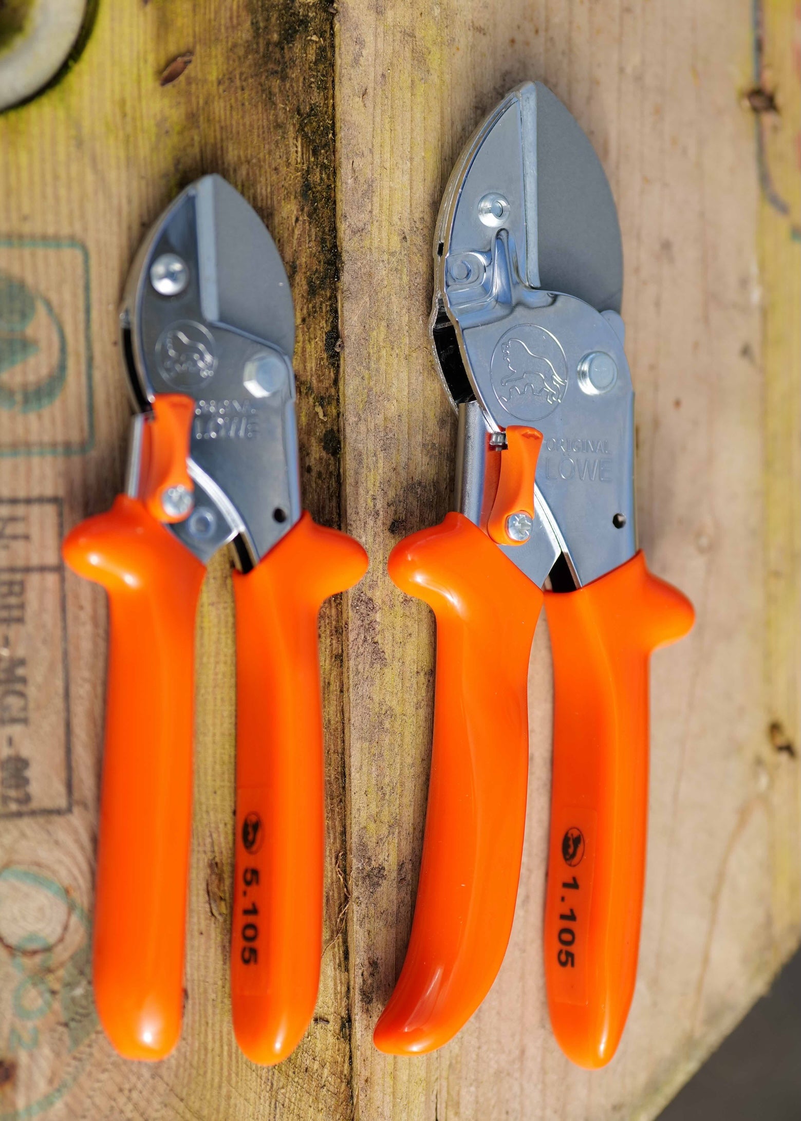 Lowe Universal Anvil Cutters and Lowe Small Anvil Cutters with silver metal blades, arranged vertically on a rustic wooden surface.