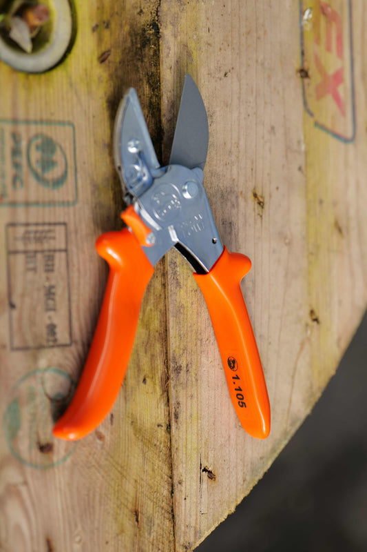 A pair of Lowe Universal Anvil Cutters with bright orange handles and silver metal blades, resting on a rustic wooden surface.